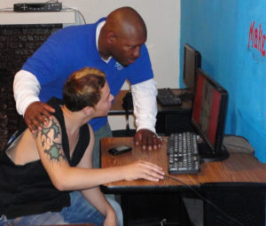 Man helping young adult use a computer